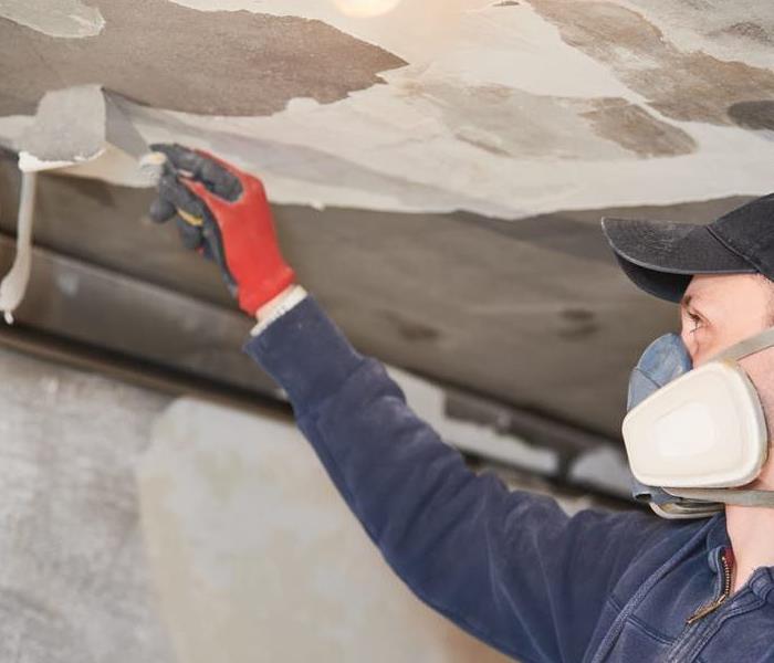 A service technician removes soot damage from a burned ceiling.