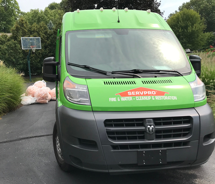 A SERVPRO service van sits outside a home being cleared of wet insulation.
